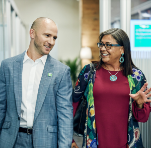 Humble Leader (1) Two TD employees walking through an office hall and conversing in light conversation. v