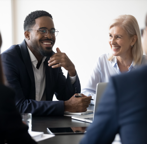 Team Norms (1) Group of colleagues together in an office smiling and looking joyful.